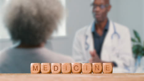 Medical-Concept-With-Wooden-Letter-Cubes-Or-Dice-Spelling-Medicine-Against-Background-Of-Doctor-Talking-To-Patient